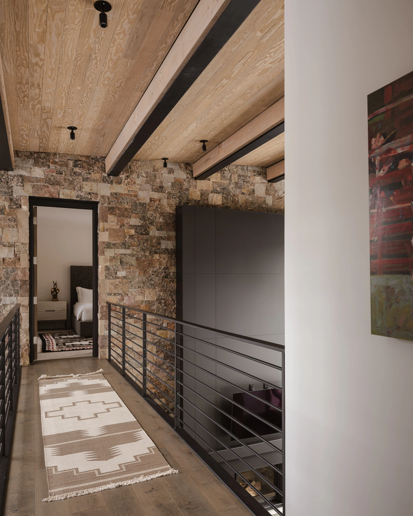 Upper-level catwalk hallway above the stacked-stone great room — architectural photography Big Sky Montana, Reid Smith Architects